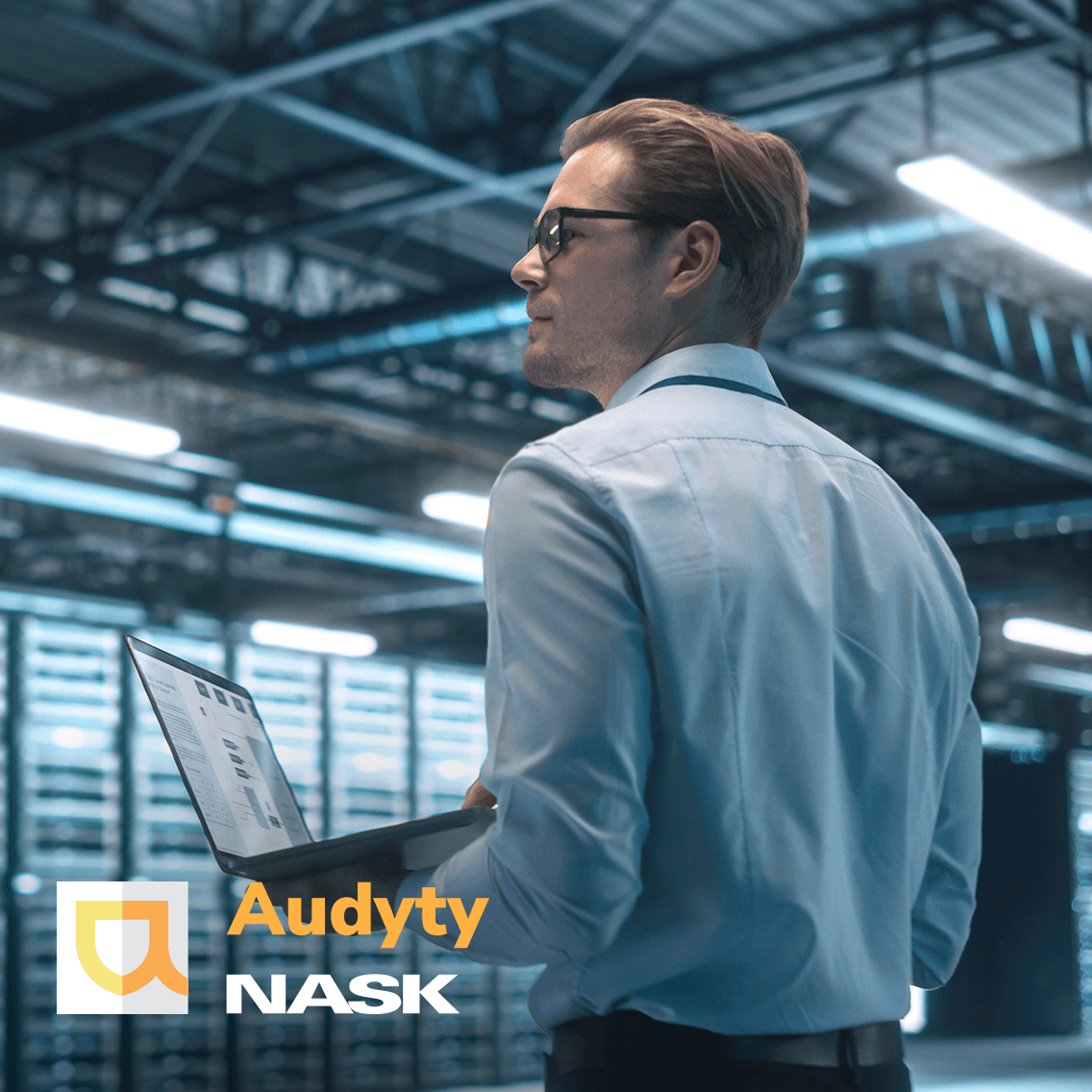 Mężczyzna stojący na tle serwerowni z komputerem w ręku