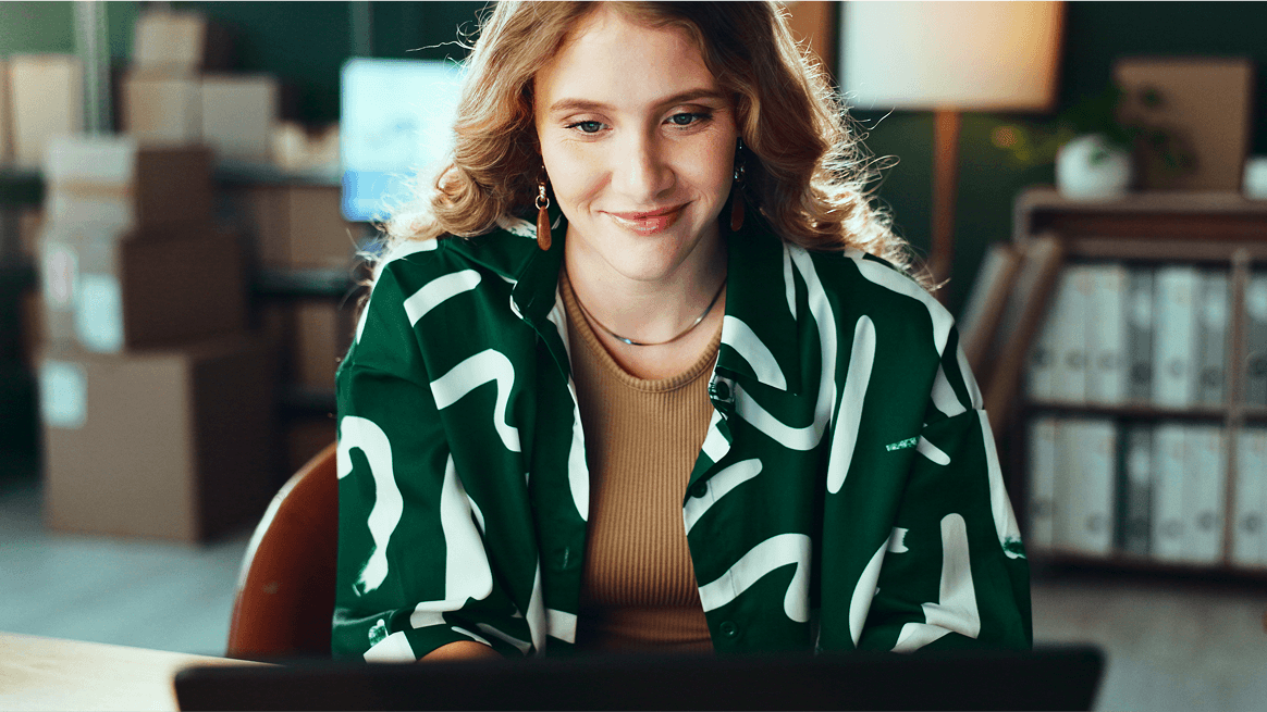 Kobieta we wzorzystej koszuli siedząca przed komputerem